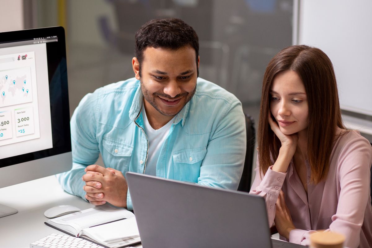 Por qué tu negocio necesita una página web profesional. Dos personas revisando el sitio web de su negocio en una computadora portátil, analizando resultados y estadísticas de crecimiento digital.